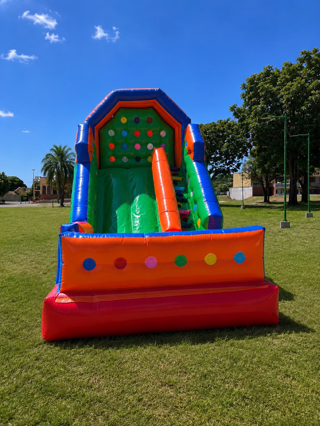 Tobogã inflável alto da Sorriso Kids, com parede de escalada verde e escorregador, montado em um gramado
